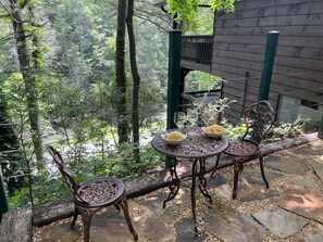 An outdoor patio with a table and chairs, surrounded by a wooden fence and lush greenery. - RR Vacation on the Rocks (Blue Ridge)