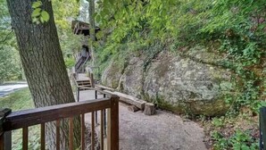 A wooden staircase leading up a rocky hillside with a wooden railing at the top.