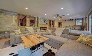 A spacious living room with a sectional sofa, a wooden coffee table, and a fireplace. - Rustic Cabin on the rapids of Toccoa River  (Blue Ridge)