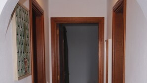 A hallway with a tiled floor, wooden doors, and a ceiling light fixture. - APARTAMENTO FAMILIAR (Caleta de Famara)
