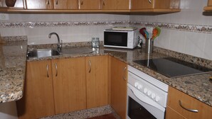 A kitchen with wooden cabinets, a stainless steel sink, a microwave, and a dishwasher. - APARTAMENTO FAMILIAR (Caleta de Famara)