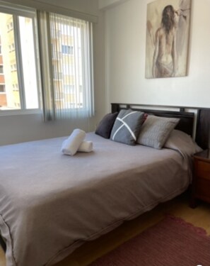 Relax in a serene bedroom with a large bed, a painting above, and a view of the outside.
