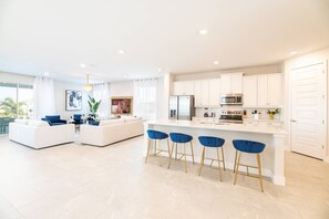 A modern kitchen with white cabinets, a stainless steel refrigerator, and a microwave. - Colorful Getaway with Home Theater at Encore (Kissimmee)