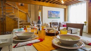 Un espace repas doté d’un plafond en bois, d’un escalier et d’un tableau au mur.