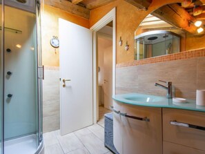 Enjoy a refreshing shower in the bathroom, featuring a glass-enclosed shower area and a spacious glass sink with a modern faucet.