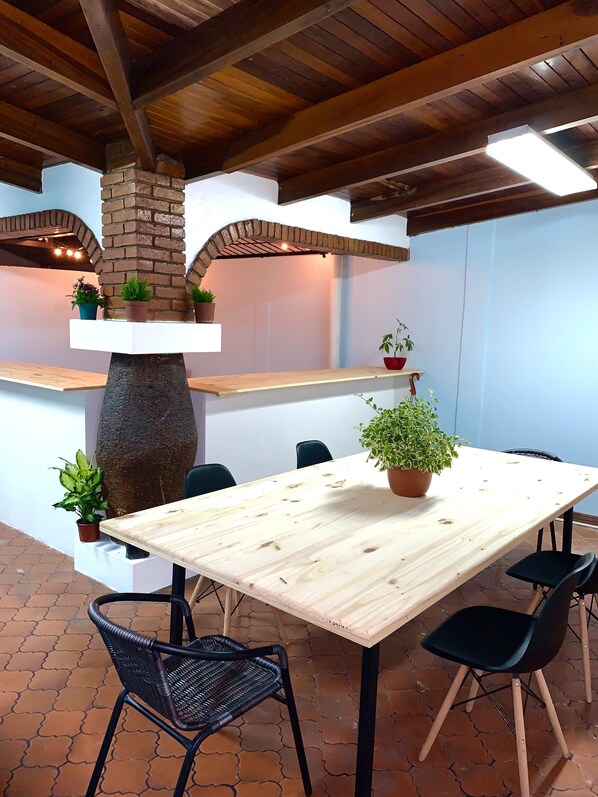A restaurant with a rustic interior, featuring exposed brick walls, wooden beams, and a large stone planter. - Global House Costa Rica Backpackers (Alajuela)