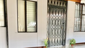 A building entrance with a metal gate, potted plants, and a tiled floor. - Global House Costa Rica Backpackers (Alajuela)