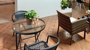 A cozy indoor seating area with wicker chairs, a glass table, and potted plants. - Global House Costa Rica Backpackers (Alajuela)
