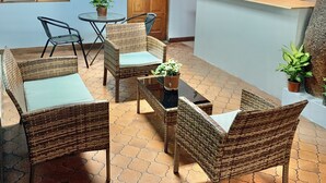 A cozy outdoor seating area with wicker furniture and potted plants. - Global House Costa Rica Backpackers (Alajuela)
