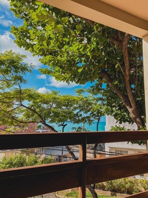 A balcony with a view of a tree and a building.