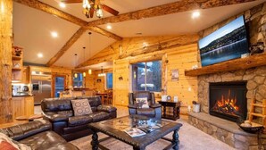 A log cabin interior with a living room, fireplace, kitchen, and dining area. - Sky Ridge. Movie Room. Games. Views. Spa. BBQ. (Big Bear Lake)