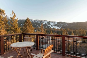 Una terraza con mesa y sillas, con vista a una zona montañosa boscosa.
