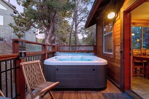 Una terraza de madera con un jacuzzi, una silla y un cartel que indica prohibido fumar.