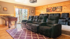 A living room with a fireplace, a sofa, a rug, and a wooden wall. - Sky Ridge. Movie Room. Games. Views. Spa. BBQ. (Big Bear Lake)