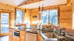 A wooden cabin interior with a kitchen featuring granite countertops, a sink, and a built-in oven. - Sky Ridge. Movie Room. Games. Views. Spa. BBQ. (Big Bear Lake)