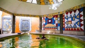 Una piscina con paredes de mosaicos geométricos de colores y una vista despejada del interior.