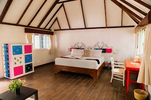 Un dormitorio con una cama de madera, una silla roja, una mesita pequeña y un armario colorido.
