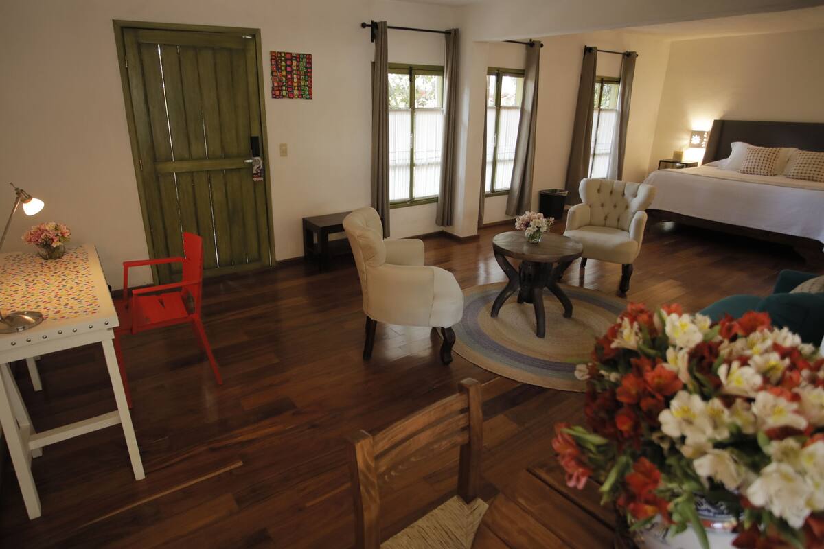 Una habitación amplia con una cama, un escritorio, una silla y una mesa redonda.