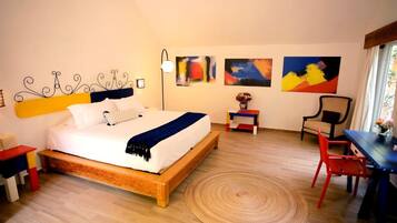 Un dormitorio con una cama de madera, un escritorio, una silla y obras de arte en las paredes.
