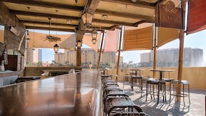 A bar area with a long counter, multiple chairs, and hanging lights.