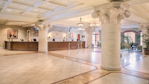 A spacious lobby with a reception desk, large columns, and a chandelier.
