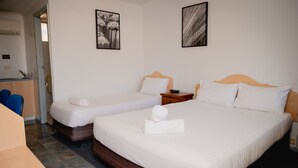 Ein Hotelzimmer mit zwei Einzelbetten, einem Holzkopfende, einem kleinen Nachttisch und einem Stuhl.