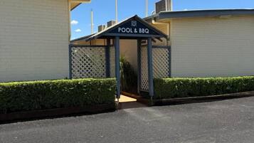 A building with a sign reading 'POOL & BBQ' indicating a recreational area.