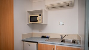 Eine kleine Küchenzeile mit Mikrowelle, Spüle und kleinem Kühlschrank.
