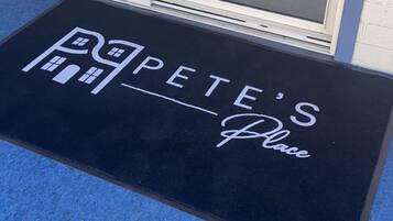 Alfombra de entrada con el texto "Pete's Place" y un icono de casa.
