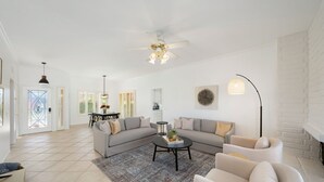A spacious living room with a sectional sofa, a round coffee table, and a fireplace. - Stylish 3 bedroom condo w/ office & 3 pools (Palm Desert)