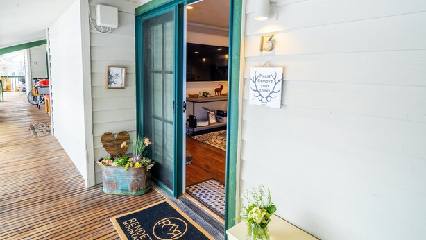 A hotel entrance with a wooden floor, a green door, and a welcome mat. - RMR: Spruces 13 - The Elks Condo in The Aspens (Wilson)