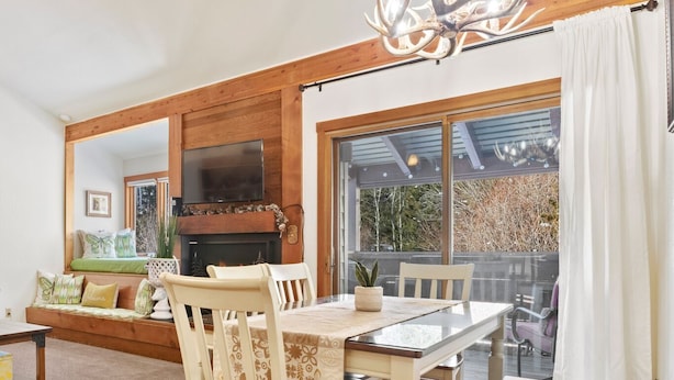 A dining area with a wooden table and chairs, a fireplace, and a large mirror. - RMR: Hawthorne 222 Condo in The Aspens/Wilson,WY (Wilson)