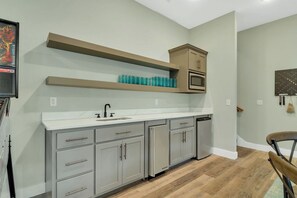 A kitchen with grey cabinets, a white countertop, and a microwave.