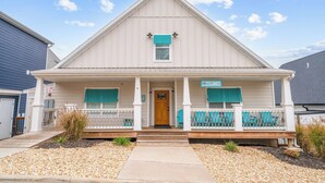 Ein eingeschossiges Haus mit Satteldach, einer Veranda mit Sitzbank und einem kleinen Vorgarten mit Kies und Pflanzen.