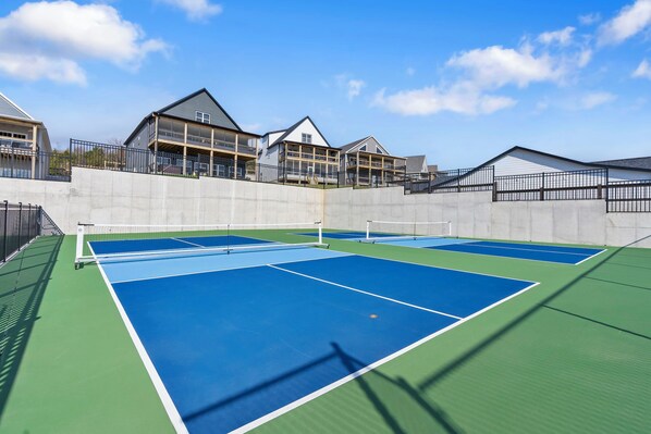 A tennis court with a net, surrounded by a concrete wall and a metal fence.