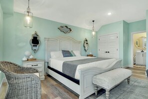 A bedroom with a bed, bedside tables, a chair, and a bench.