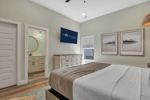A bedroom with a bed, a dresser, a mirror, and artwork on the wall.