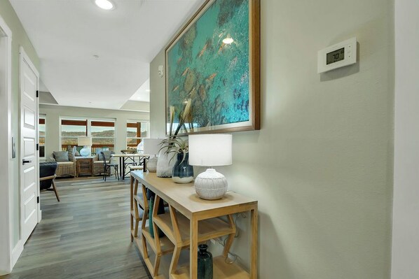 A hallway with a wooden console table, a painting, and a thermostat.