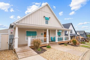 A single-story house with a front porch, a covered entryway, and a small front yard with gravel and plants.