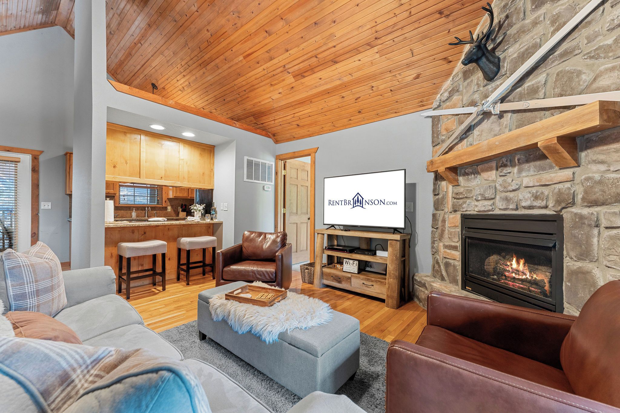 A modern living room with a fireplace, a television, and a kitchen area.