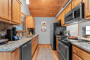 A kitchen with wooden cabinets, a stainless steel refrigerator, a microwave, a stove, and a coffee maker.