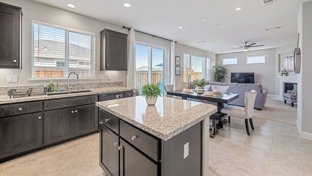 A modern kitchen with dark cabinets, granite countertops, and a central island.