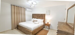 Une chambre à coucher avec un lit en bois, une table de chevet avec une lampe, un miroir et une citation encadrée accrochée au mur.