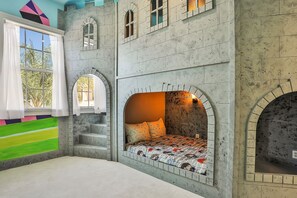 A bedroom with a castle-themed design, including arched windows and a bed with a castle-patterned bedspread. - Oasis Villa | 5BR, 4.5 Bath Luxe Home w/ Private Pool, Arcade, and Theater Near Orlando Theme Parks (Kissimmee)