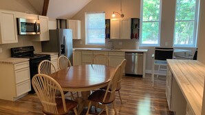 A modern kitchen with white cabinets, a wooden dining table, and a built-in oven. - Waterfront King Beds Pet Friendly Deck Home with Dock & Views. (Eutawville)