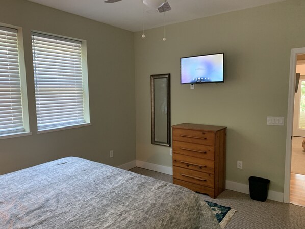 Un dormitorio con cama, cómoda, televisor y espejo.