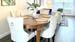 Un comedor con una mesa redonda de madera, sillas blancas tapizadas y una lámpara decorativa.