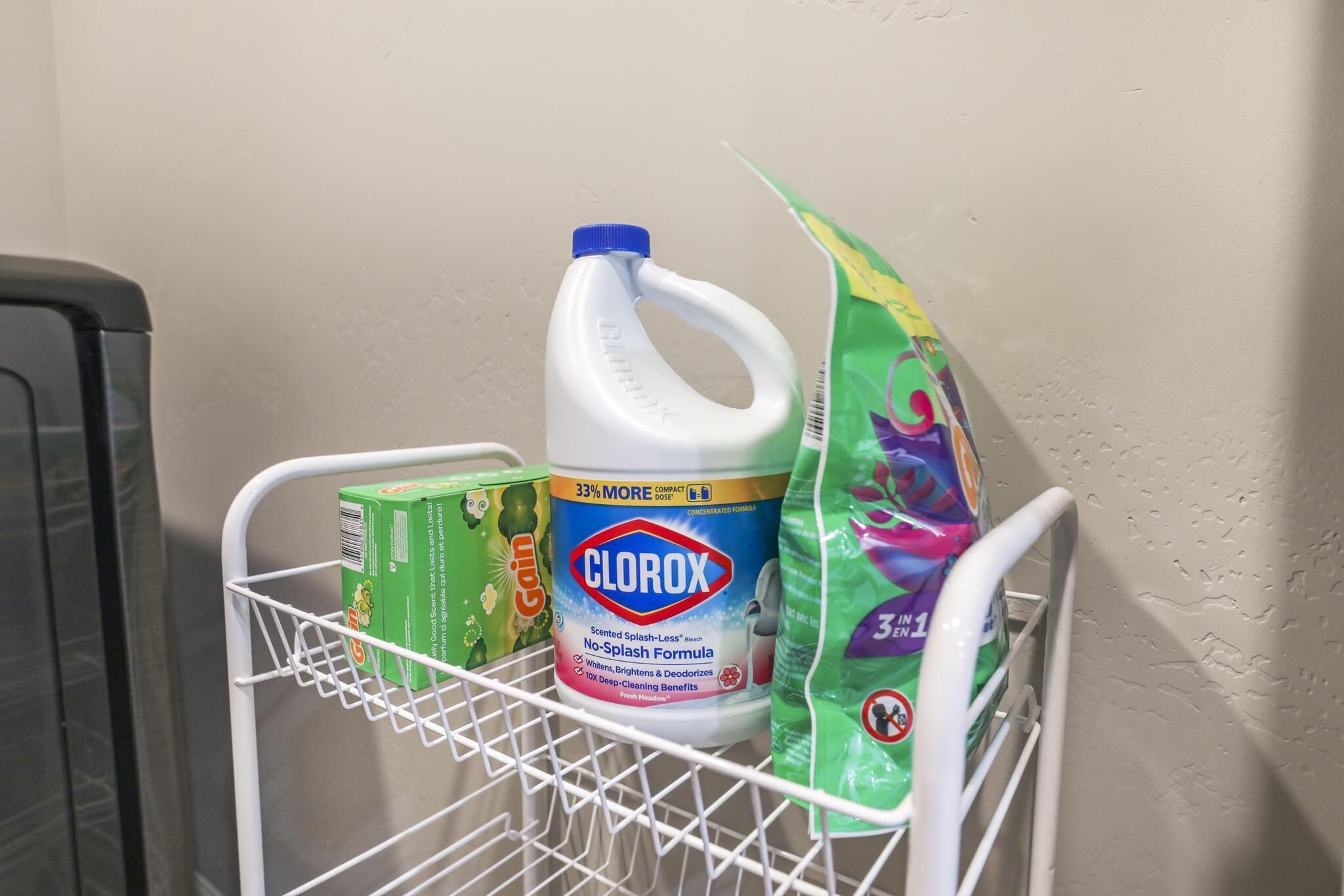Un chariot contenant des produits de nettoyage, avec une bouteille de désinfectant Clorox, une boîte de liquide vaisselle Gain et un sac de produit nettoyant multi-usages.