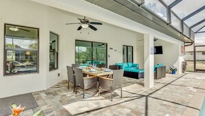 Un espacio cubierto con patio, una mesa de comedor, sillas y un ventilador de techo.