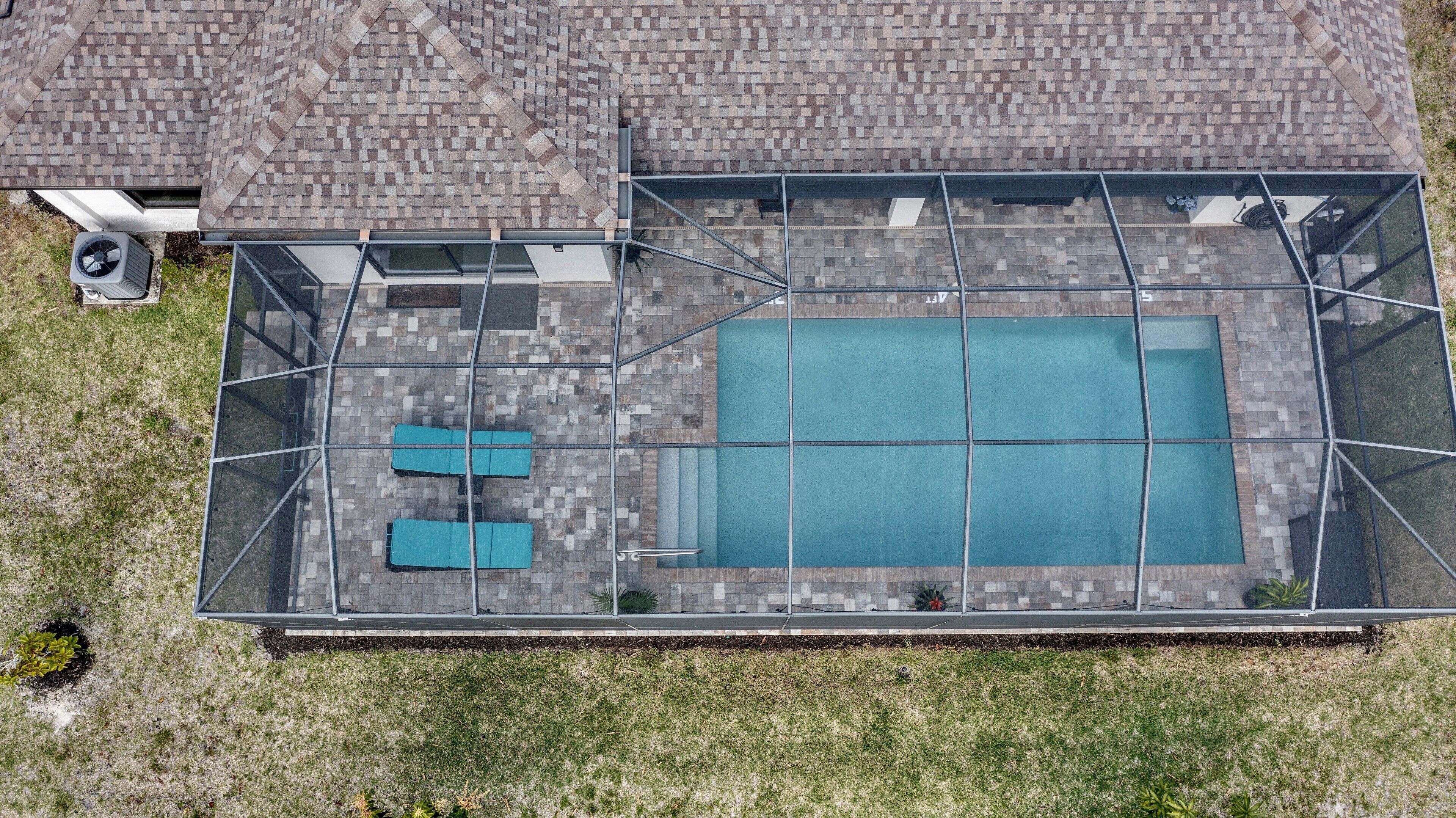 Ein Luftbild von einem Dachpool mit Glasumrandung, zwei Liegestühlen und einer kleinen Sitzecke.